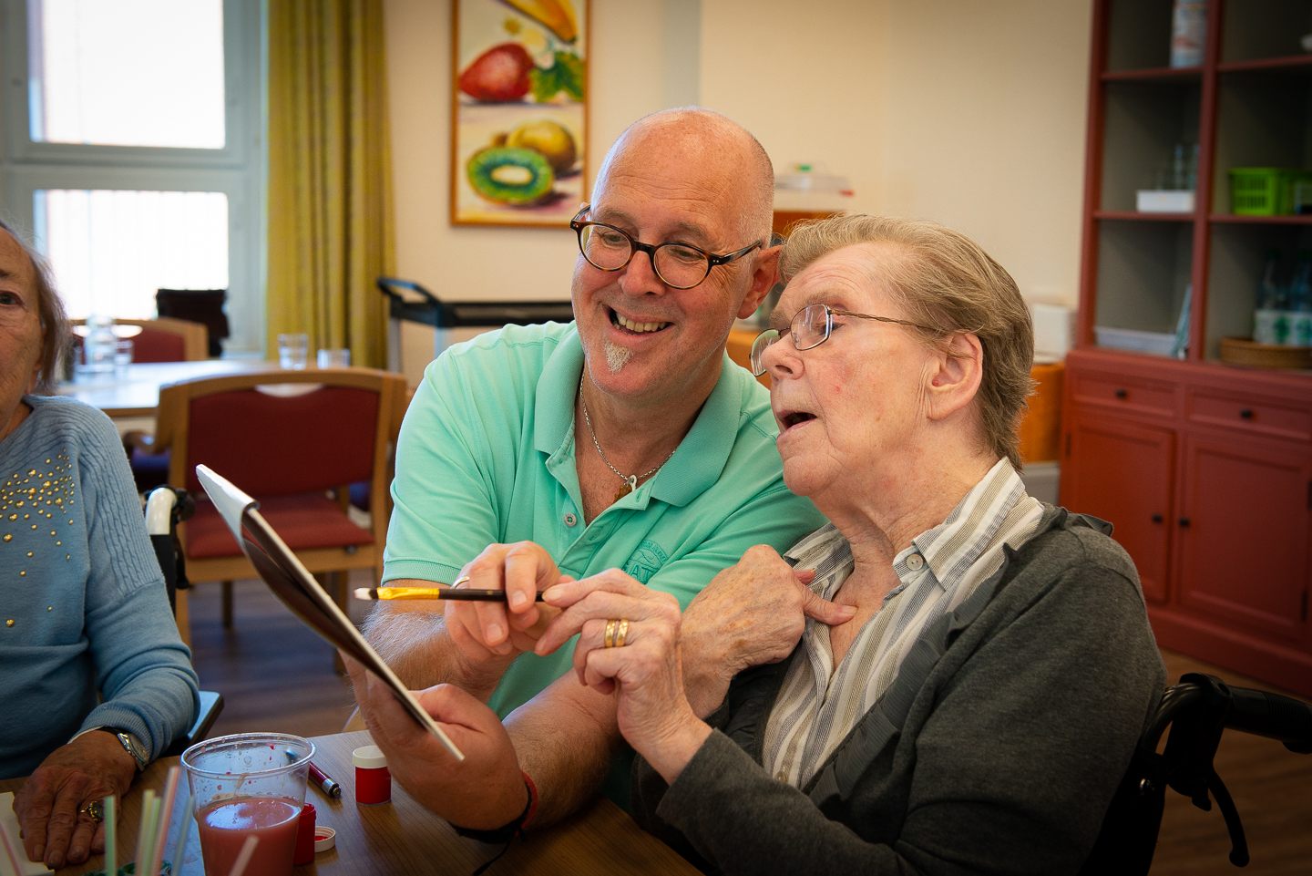 Ein Betreuer malt gemeinsam mit einer Bewohnerin
