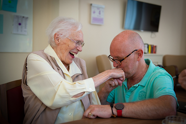 Ein Pfleger küsst die Hand einer Bewohnerin